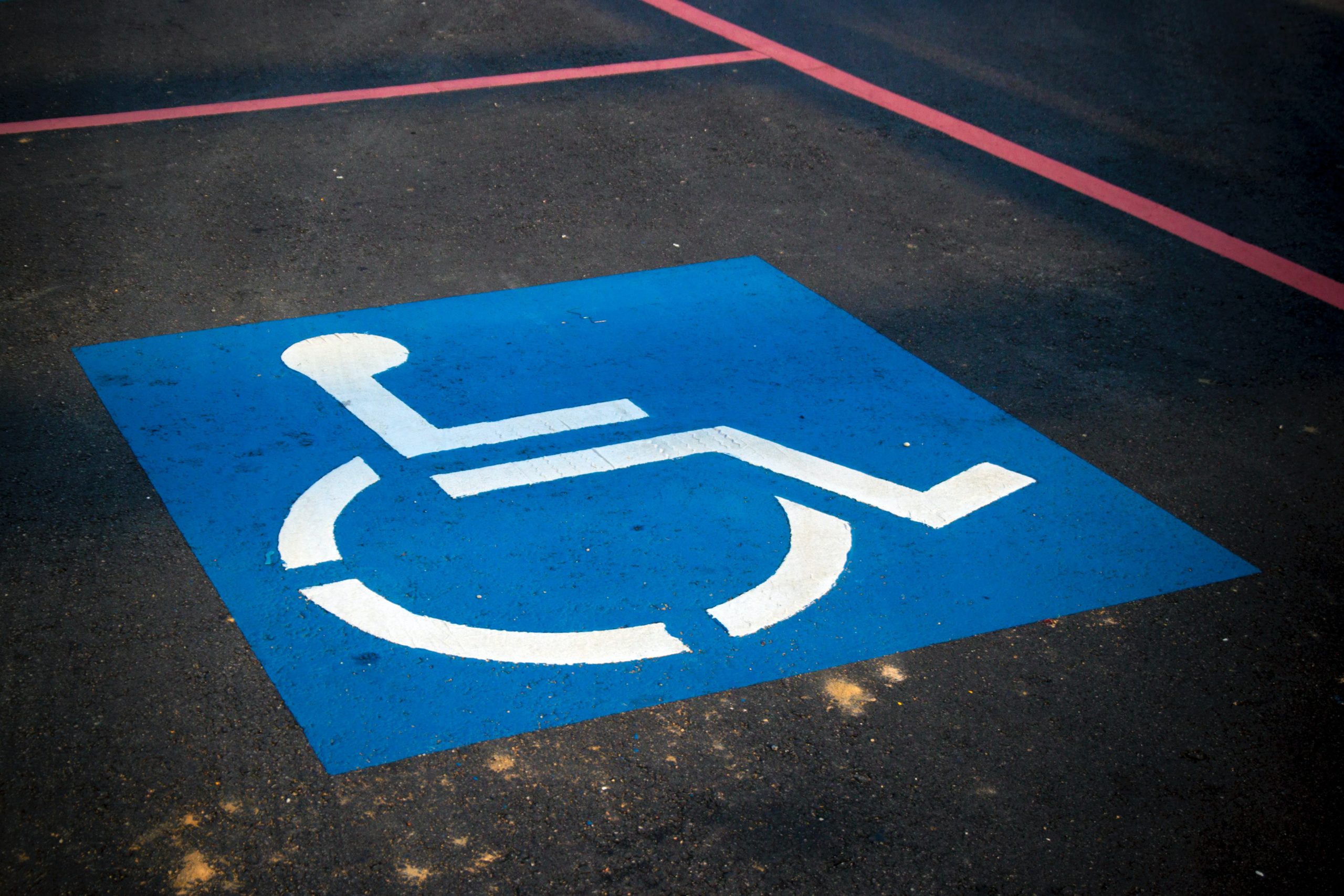 Symbol mit weißem Rollstuhlfahrer auf blauem Grund