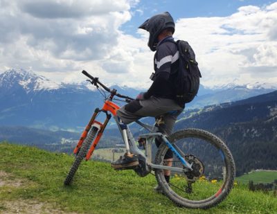 Ein Mann mit Prothese sitzt auf seinem Fahrrad und schaut in die Berge.